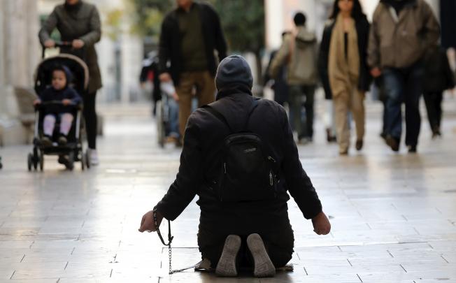 A man begs outside at a market in Valencia, eastern Spain. The World Bank has warned that a slow recovery in developed nations is acting as a brake on the global economy. Photo: EPA