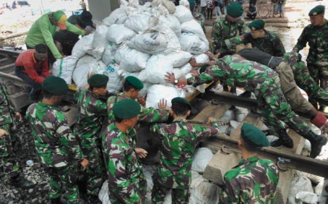 Indonesian military stack sandbags to stop the flow of water from a collapsed river wall in Jakarta on January 19. Photo: AFP