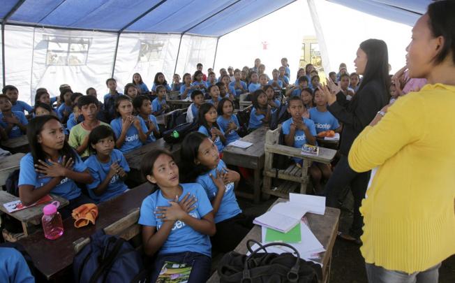 A class is held in a tent at an evacuation centre. Photo: Reuters