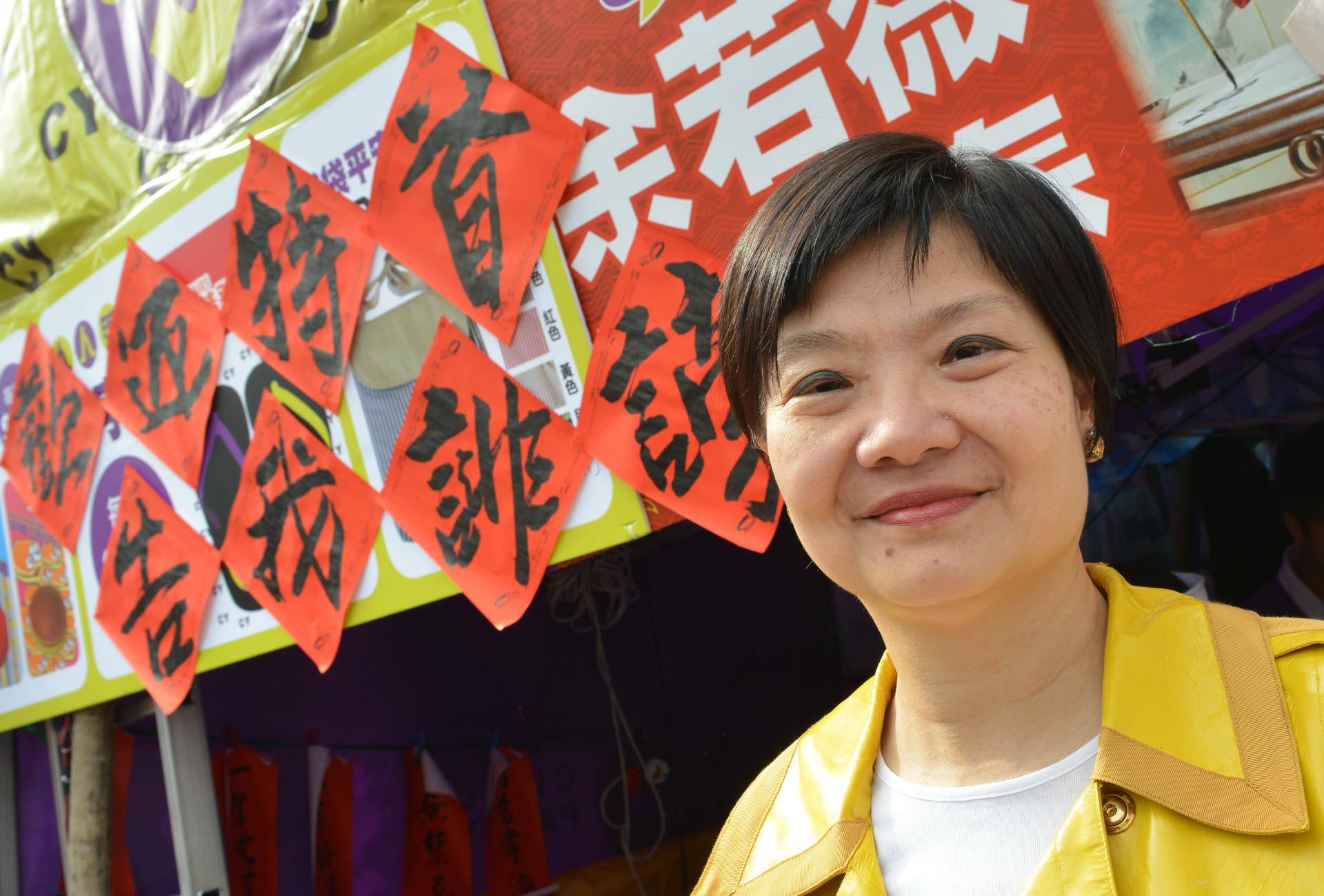 Audrey Eu, chairman of the Civic Party poses yesterday with the couplets she wrote, inviting the chief executive to sue her for defamation, in a reference to the news that C.Y. Leung had sent a legal letter to the Economic Journal. Photo: Thomas Yau