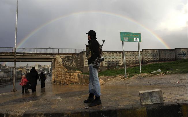 A member of the Free Syrian Army stands with his weapon as he looks at a rainbow in Aleppo on Saturday. Photo: Reuters