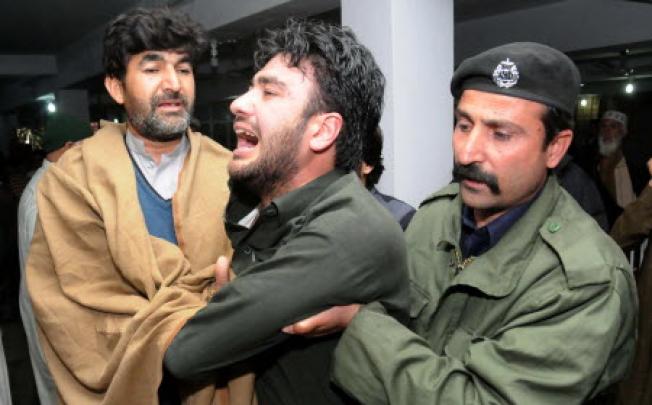 People comfort a man whose relative was killed when a bus fell into a Canal, at a local hospital in Peshawar. Photo: EPA