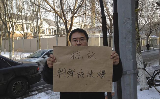 A protester holding a sign poses for a photo outside the North Korea consulate in Shenyang. Photo: Reuters
