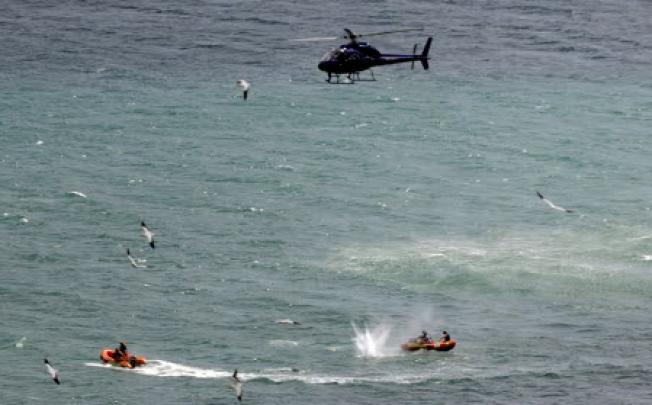 Police in inflatable rubber boats shoot at a shark off Muriwai Beach near Auckland, New Zealand, on Wednesday. Photo: AP