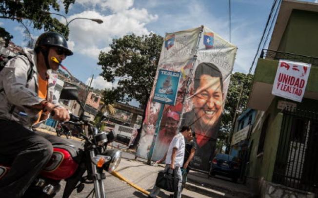 People crosses in front of a billboard showing Venezuelan President Hugo Chavez, outsides the Military Hospital in Caracas. Photo: EPA