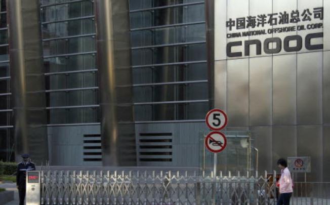 A woman walks past the entrance of the headquarters of China National Offshore Oil Corp (CNOOC) in Beijing. Photo: Reuters