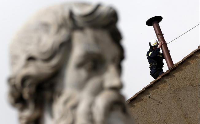 A fireman fits a chimney on the roof of the Sistine Chapel at the Vatican from which white smoke will issue to prepare when the conclave of Catholic cardinals elects a successor to Pope Benedict. Photo: Reuters