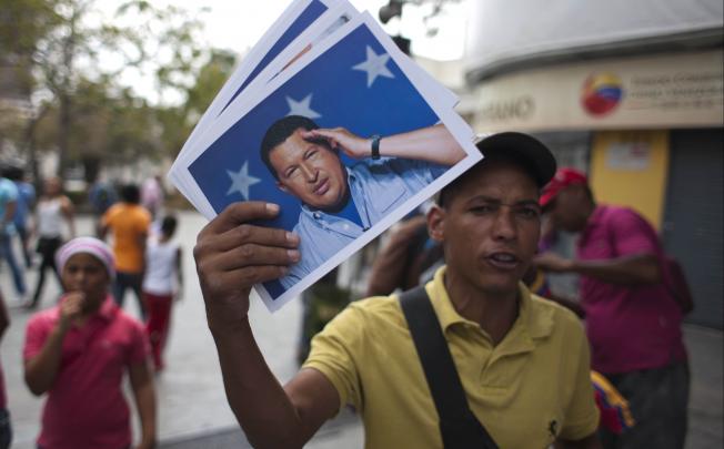 A man sells photos of the late Venezuelan President Hugo Chavez at the Simon Bolivar Square, in Caracas, Venezuela. Photo: Xinhua