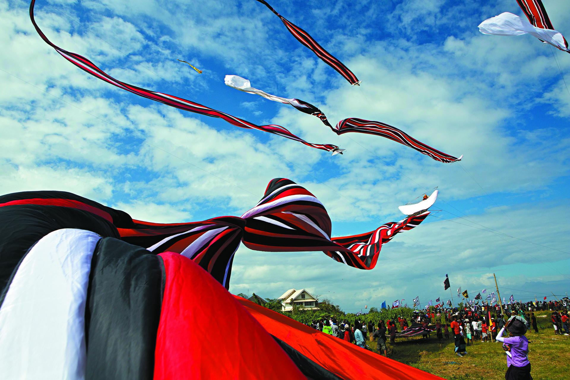 Traditional black, red and white kites take to the skies at the Bali Kite Festival in Pantai Padang Galak, Sanur.