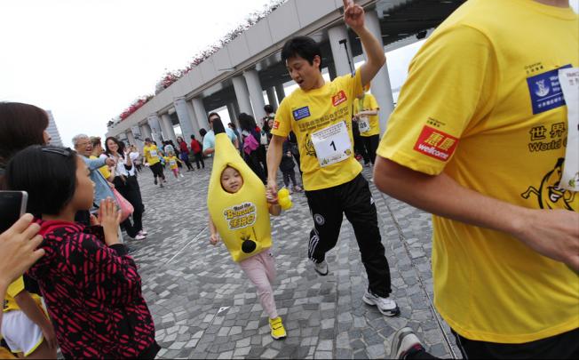 Little kids and big kids go bananas on the Tsim Sha Tsui promenade yesterday in the eighth Beat the Banana charity run. With a new 1km children's route, more than 1,600 bananas did the run - watched by people dressed as corn, strawberries and other healthy treats. The race raises money for cancer prevention awareness. Photo: Nora Tam