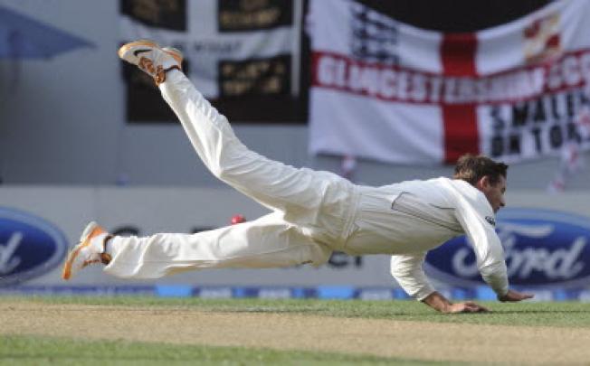 New Zealand's Bruce Martin dives to field off his own bowling against England on the second day of the 3rd international cricket test in Auckland on Saturday. Photo: AP