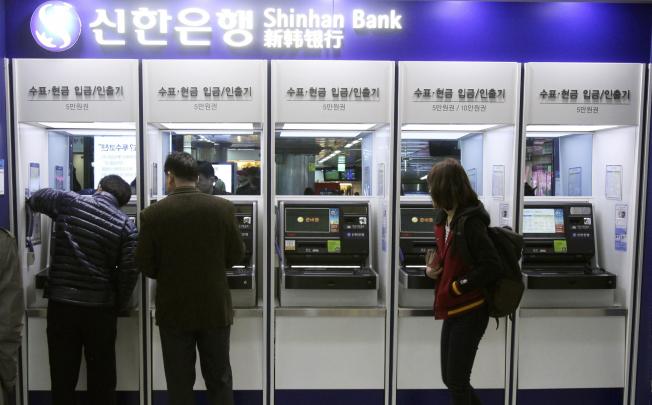 Depositors try to use automated teller machines of Shinhan Bank while the bank's computer networks are paralysed, at a subway station in Seoul. Photo: AP