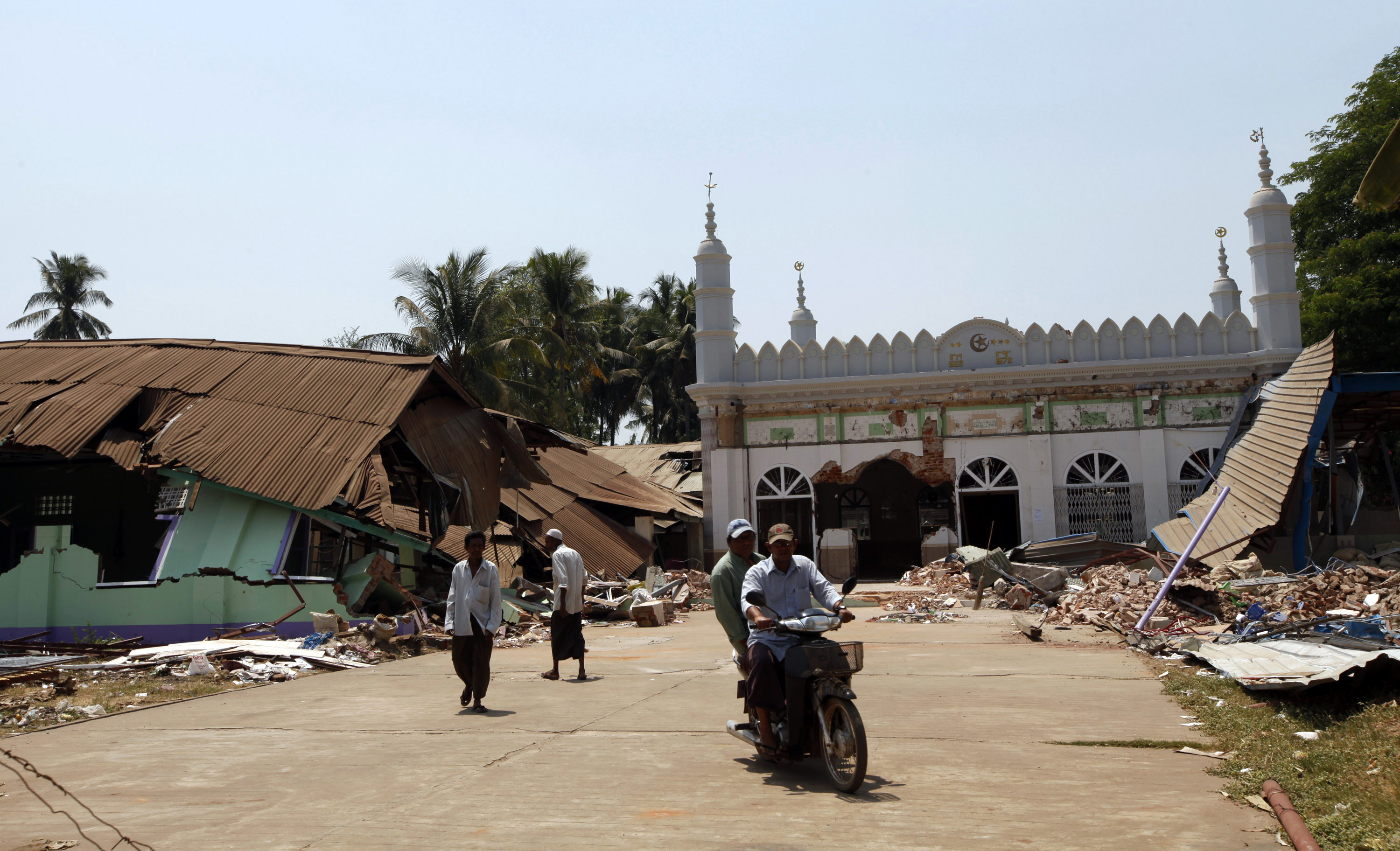 Men ride on a motorbike as others remove debris from a destroyed mosque, in Gyobingauk, about 125 miles from Yangon, Myanmar. Photo: AP