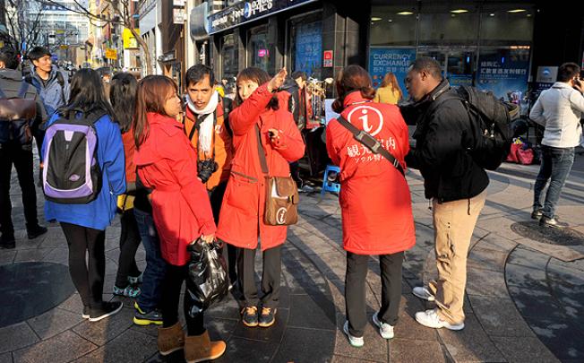 Tourists consult with tour guides in a shopping district of Seoul. Photo: AFP
