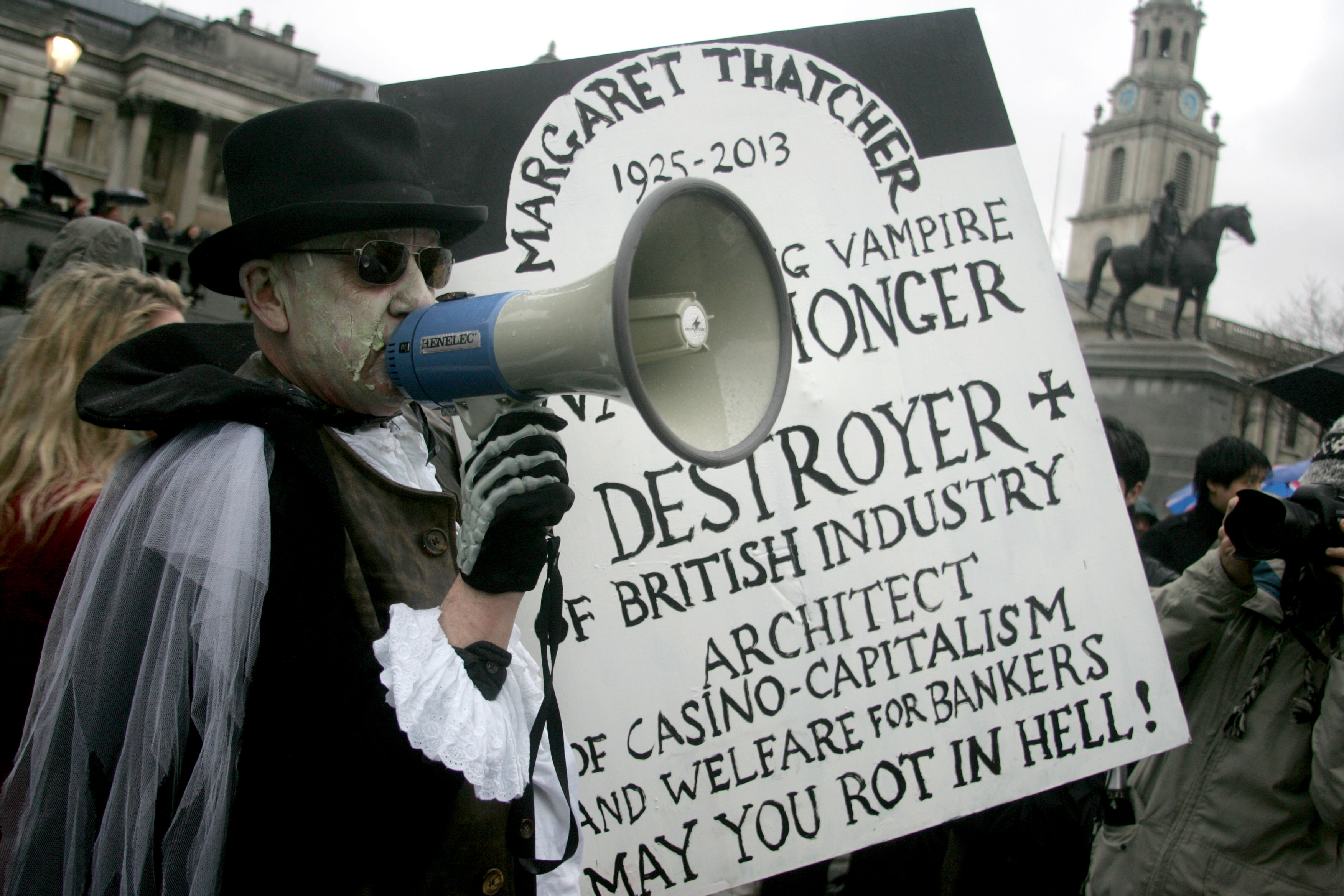A protester holds up a placard during a 'party' celebrating former British PM Margaret Thatcher's death in London's Trafalgar square. Photo: Xinhua