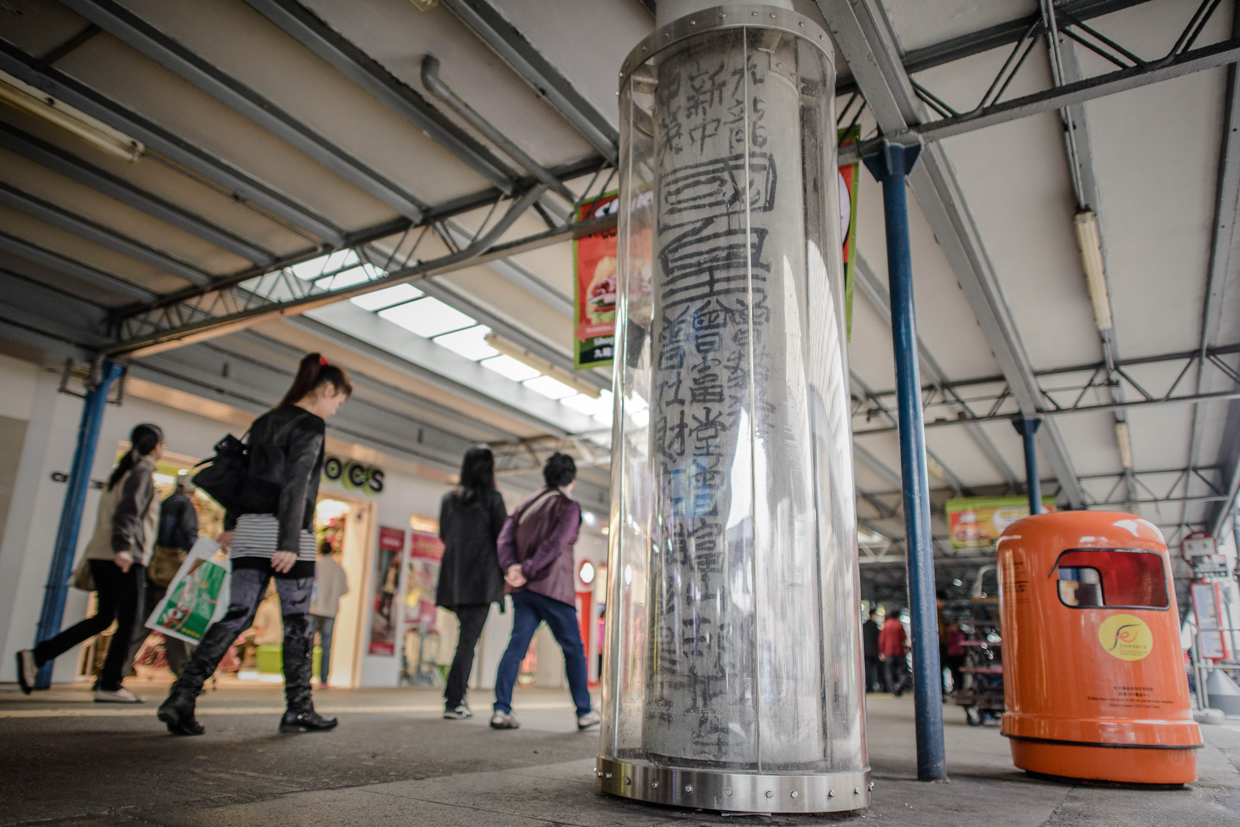 Pedestrians walk past a plastic casing set up around a graffiti made by the late self-declared "King of Kowloon", Tsang Tsou-choi, in Hong Kong. Photo: AFP