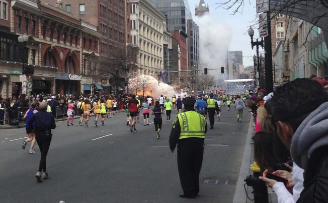 Runners continue to run towards the finish line as an explosion erupts at the finish line of the Boston Marathon. Photo: Reuters