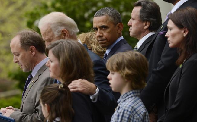 Barack Obama with the families of shooting victims. Photo: EPA
