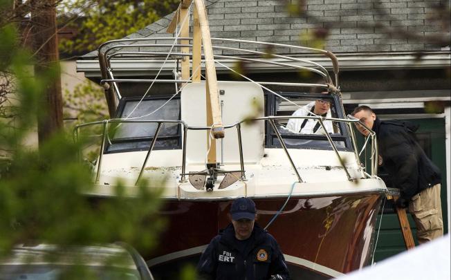 FBI investigators study the boat in Dave Henneberry's garden in Franklin Street, Watertown, where the suspect was found. Photo: Reuters