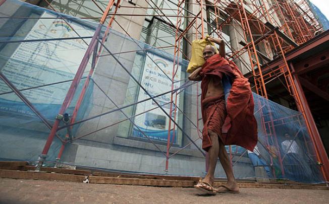 A Buddhist monk passes scaffolding of a construction site in downtown Yangon. Photo: EPA