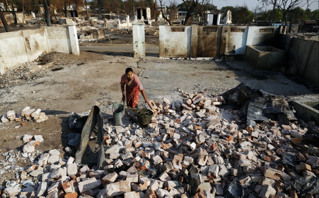 A woman collects bricks and other useful items from burnt Muslim homes in Meikhtila. Photo: Reuters