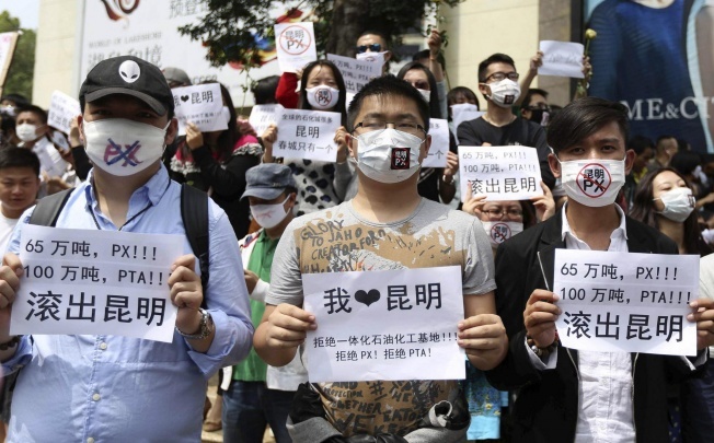 Residents wearing masks hold posters with slogans including 'PX get out of Kunming' as they protest against a planned refinery. Photo: Reuters