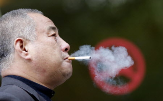 A man smokes next to a "No Smoking" sign in downtown Shanghai. US doctors are advising smokers to have CT screening for lung cancer. Photo: Reuters