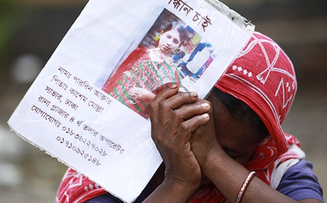 A woman cries holding the photo of her missing daughter on the thirteenth day of the Rana Plaza building collapse, in Savar, Dhaka, on Wednesday. Photo: EPA