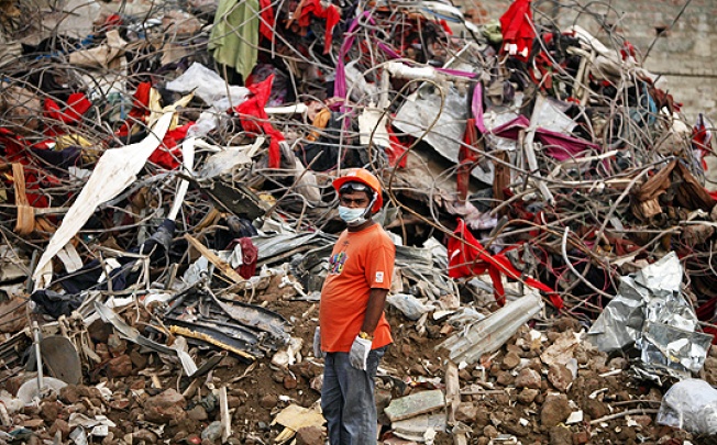 A Bangladeshi rescuer stands amid the rubble of a garment factory building that collapsed on April 24 as they continue searching for bodies in Savar, near Dhaka, on Sunday. Photo: AP