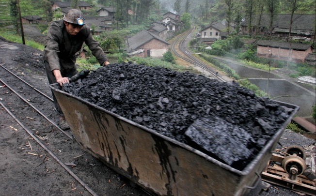 A miner pushes a cart loaded with coal at Bagou village, in China's southwest Sichuan. Photo: AP