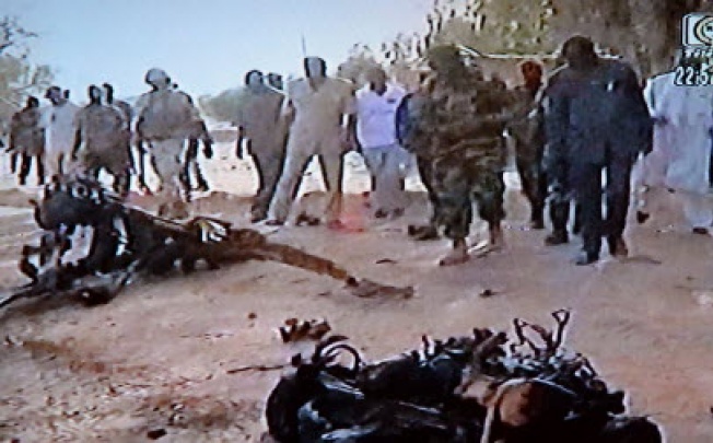 A video grab shows people standing in front of wreckage of the suicide bomber's motor vehicle at the Agadez army base, Niger, following car bombings in Niger in which at least 20 people died. Photo: AFP