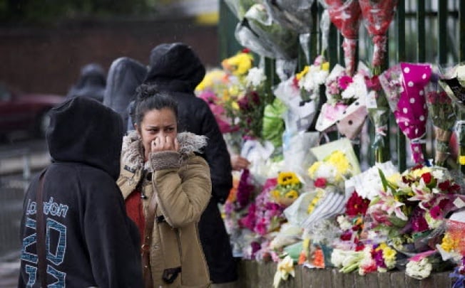 TOPSHOTSA woman reacts as she looks at floral tributes left at the scene where Drummer Lee Rigby of the 2nd Battalion was killed outside Woolwich Barracks in London. Photo: AFP