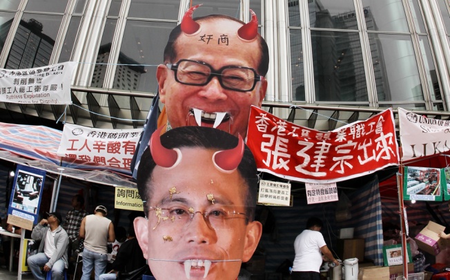 Striking dock workers put pictures of Victor Li Tzar-kuoi and his father Li Ka-shing at Cheung Kong Center in Central to voice their discontent over the poor working conditions in Kwai Chung Container Terminal. Photo: Edward Wong