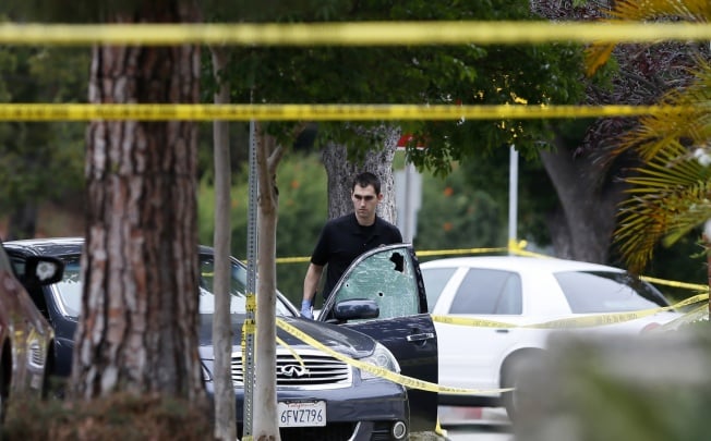A police officer is seen by a bullet riddled car outside a home which was set on fire in Santa Monica. Photo: Reuters
