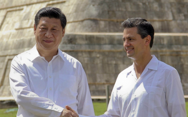 China's President Xi Jinping shakes hands with Mexico's President Enrique Pena Nieto as they visit the archaeological site of Chichen itza, State of Yucatan. Photo: AFP 