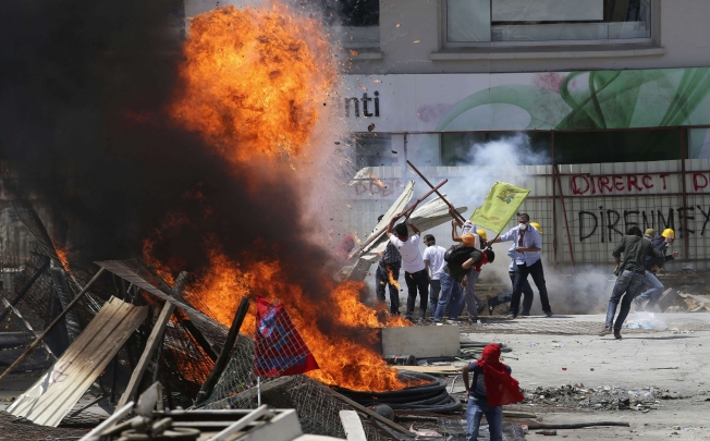 Protesters standing behind a barricade clash with riot police during a protest at Taksim Square. Photo: Reuters