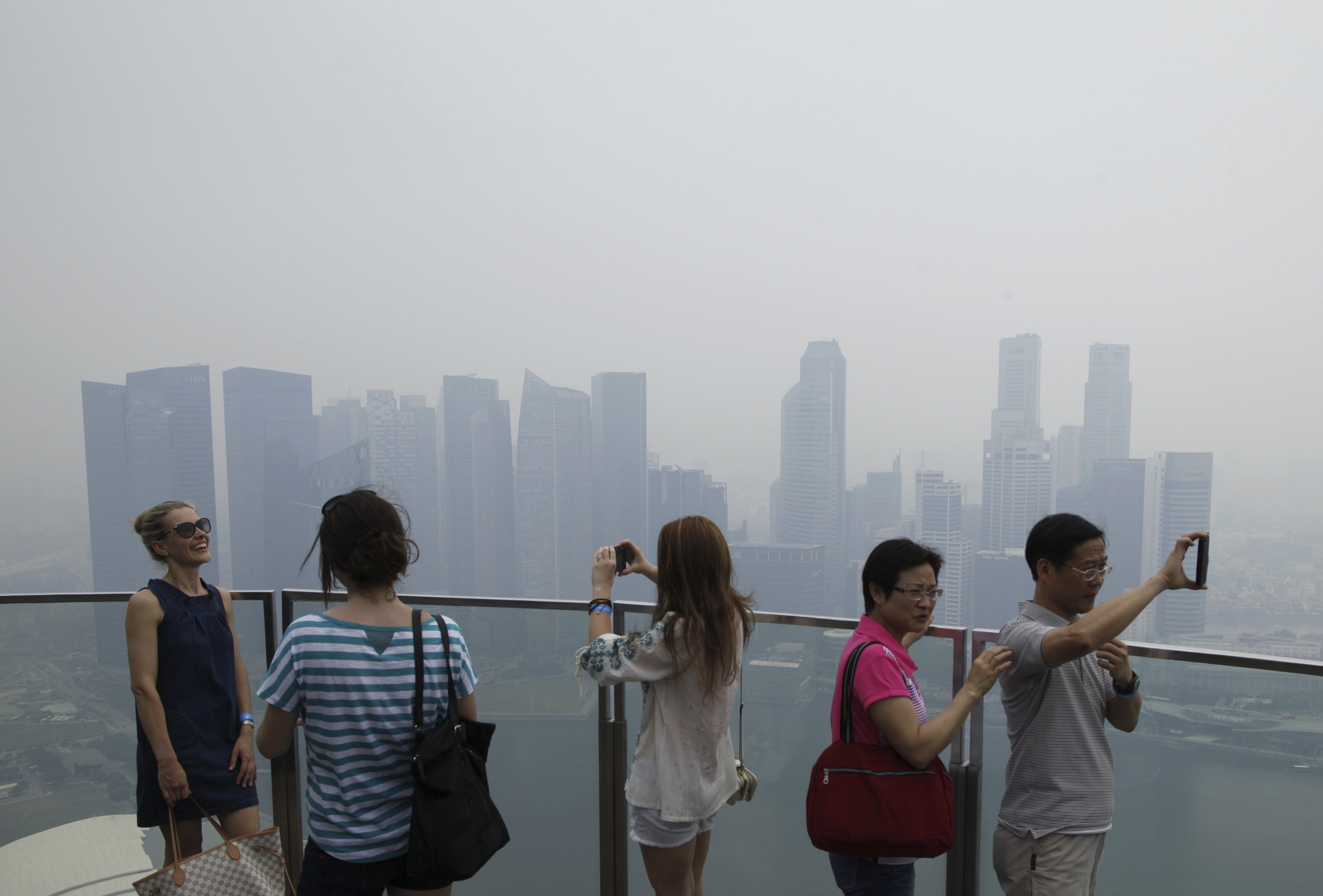 Visitors take photos on an observation deck at the Marina Bay Sands Skypark overlooking the haze covered skyline of Singapore. Photo: Reuters