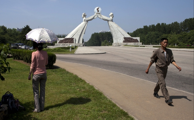 A man walks past a woman near a statue known as the Monument to the Three Charters for National Reunification in Pyongyang, North Korea. Photo: AP