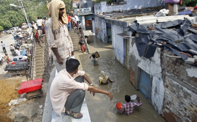 Residents carry their belongings through an alley flooded with the rising water level of river Yamuna after heavy monsoon rains in New Delhi. Photo: Reuters