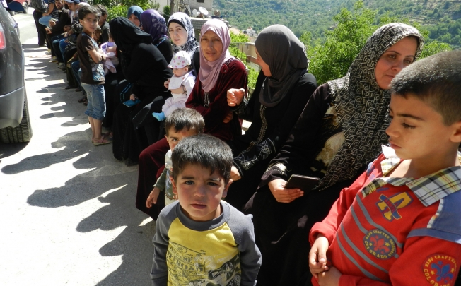 Syrian refugees wait to get aid in Shebaa region in south Lebanon. Photo: Xinhua