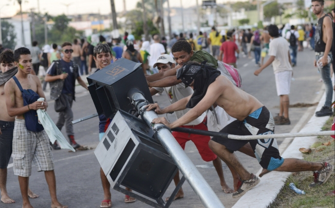 Demonstrators tear down a traffic light during clashes with riot police near the Estadio Castelao in Fortaleza. Photo: Reuters