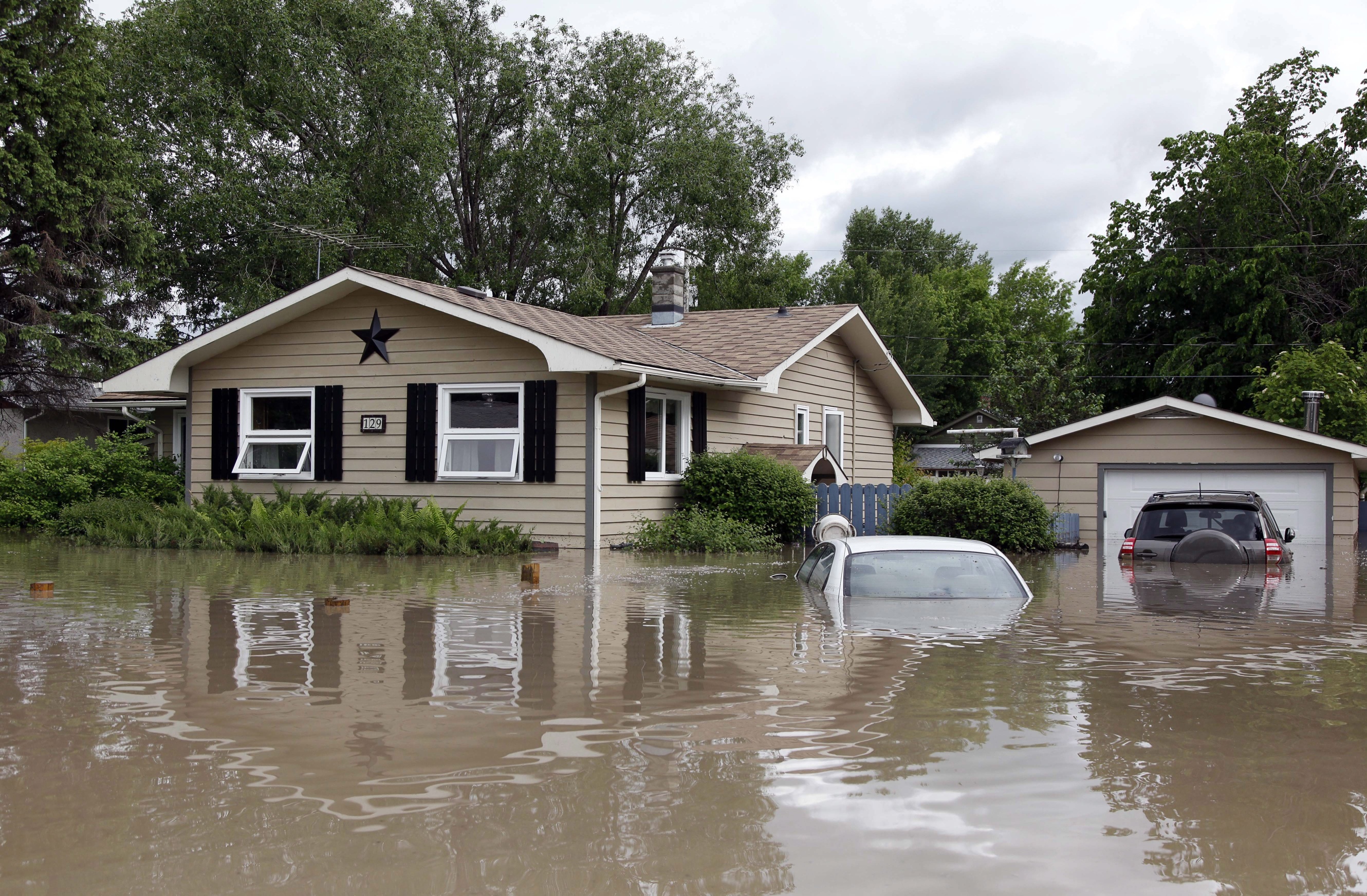 Cars and homes are submerged in flood waters in High River, Alberta. Calgary city officials say as many as 100,000 people could be forced from their homes due to heavy flooding. Photo: AP