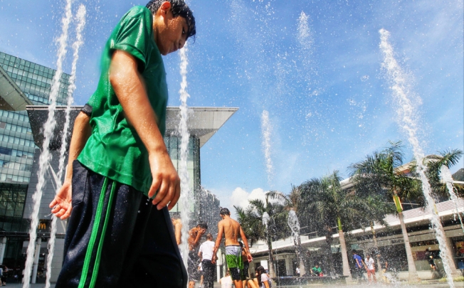 Children try to get a little relief from the heat by dousing themselves at a fountain in Tung Chung as the temperature reaches 34.2 degrees Celsius. Photo: Felix Wong