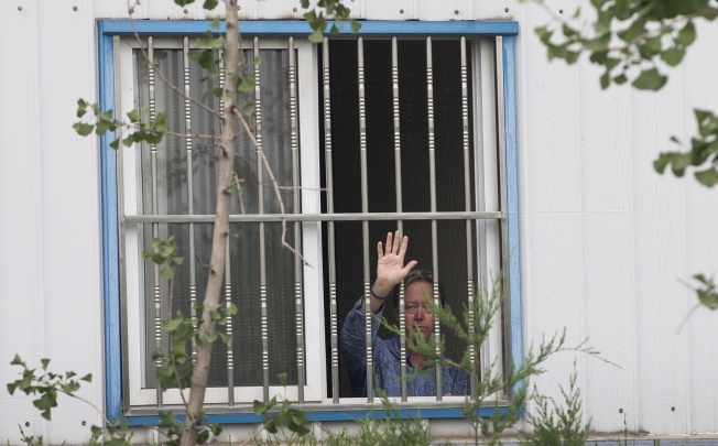 Chip Starnes waves from a window after he was held hostage by workers inside his plant at the Jinyurui Science and Technology Park in Qiao Zi near Beijing. Photo: AP