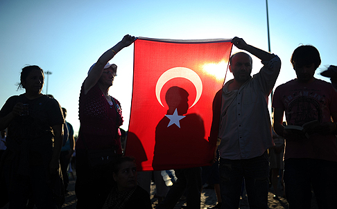 People hold a Turkish national flag as they stand on the flashpoint Taksim square in Istanbul on June 18. Photo: AFP