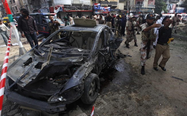 Paramilitary soldiers and police officers direct people away from the site of a bomb blast in Karachi. Photo: Reuters