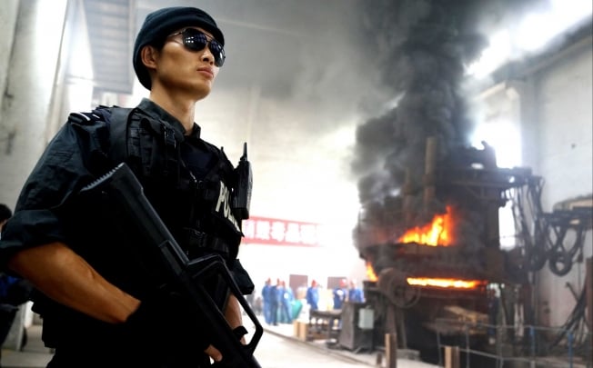A policeman stands guard as staff destroy drugs in a factory in China's Guizhou province. Photo: AFP
