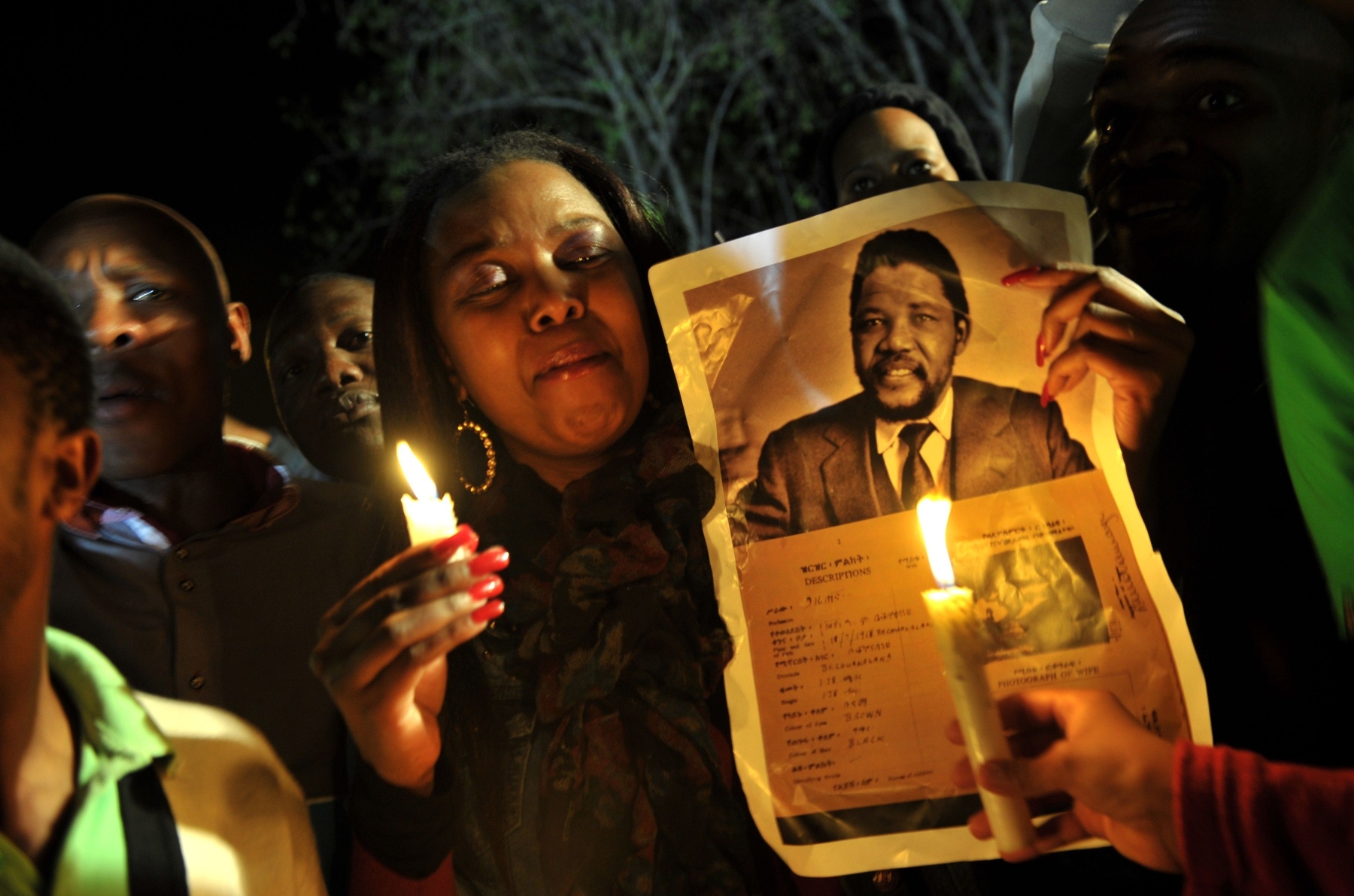 A group of well-wishers hold candles and a photo of Nelson Mandela as they pray for his recovery outside the Mediclinic heart hospital where he is hospitalised in Pretoria. Photo: AFP
