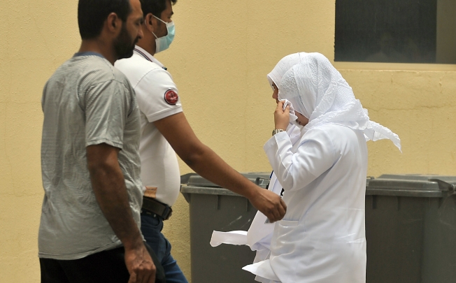 Saudi nurses and citizens walk outside the King Fahad hospital in Hofuf, Saudi Arabia. Photo: AFP