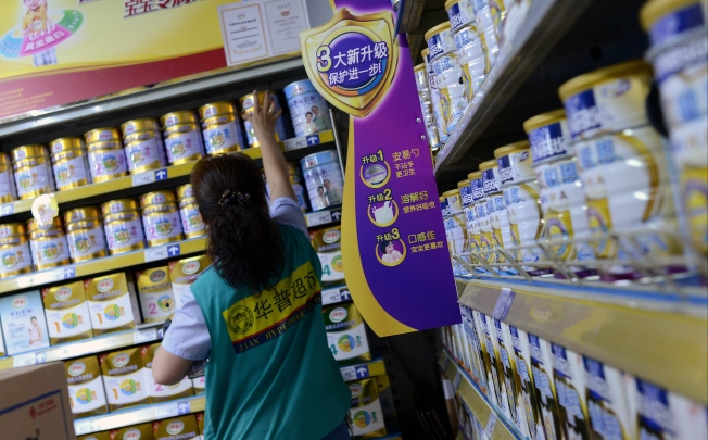 A saleswoman checks items for sale next to a shelf of milk powder at a supermarket in Beijing. Photo: AFP